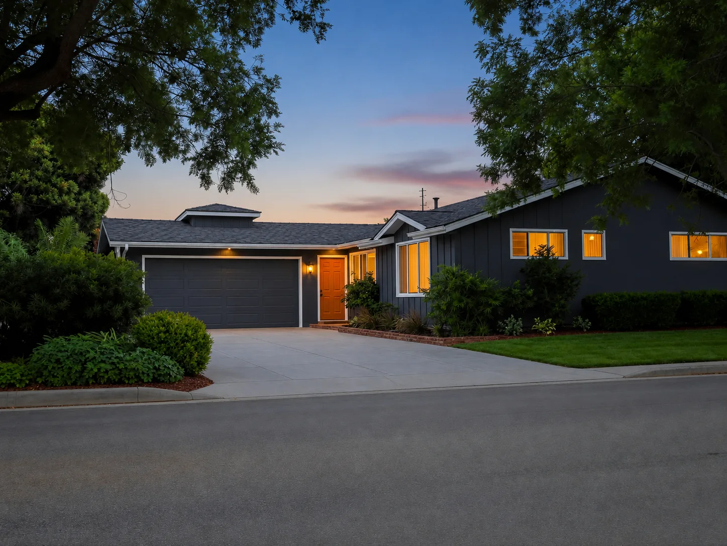 Ranch house after — deep charcoal siding, bold orange door, lush landscaping at dusk