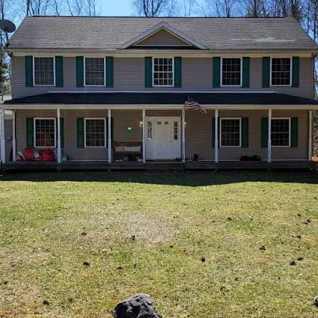 Colonial before — beige siding, green shutters, patchy lawn, dated porch